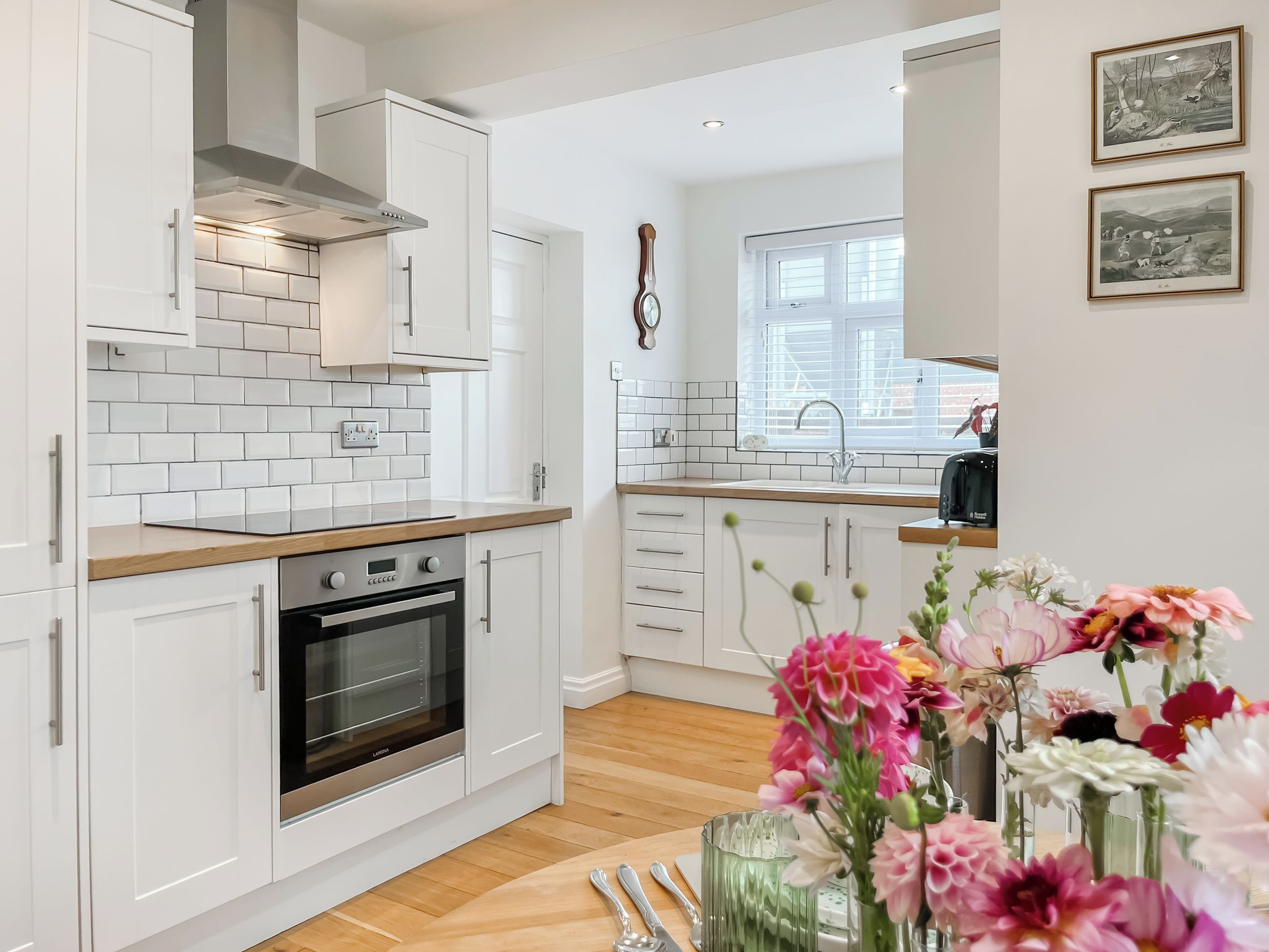 A modern kitchen with white cabinetry, a built-in oven, and a wooden countertop.