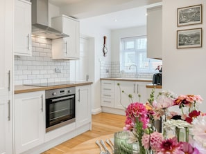 A modern kitchen with white cabinetry, a built-in oven, and a wooden countertop. - Edleston Farm Cottage - UK52358 (Edleston, near Nantwich)