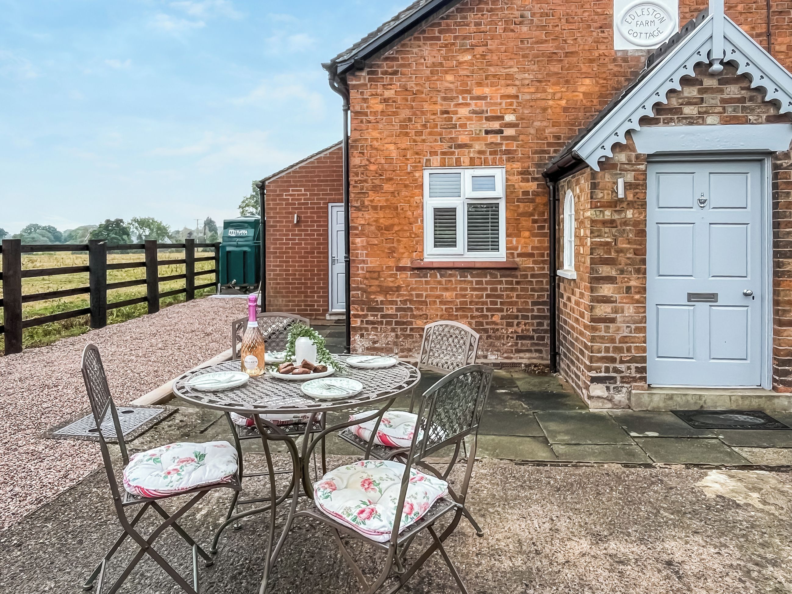 A brick building with a white door and a sign reading 'Edleston Farm Cottage.'