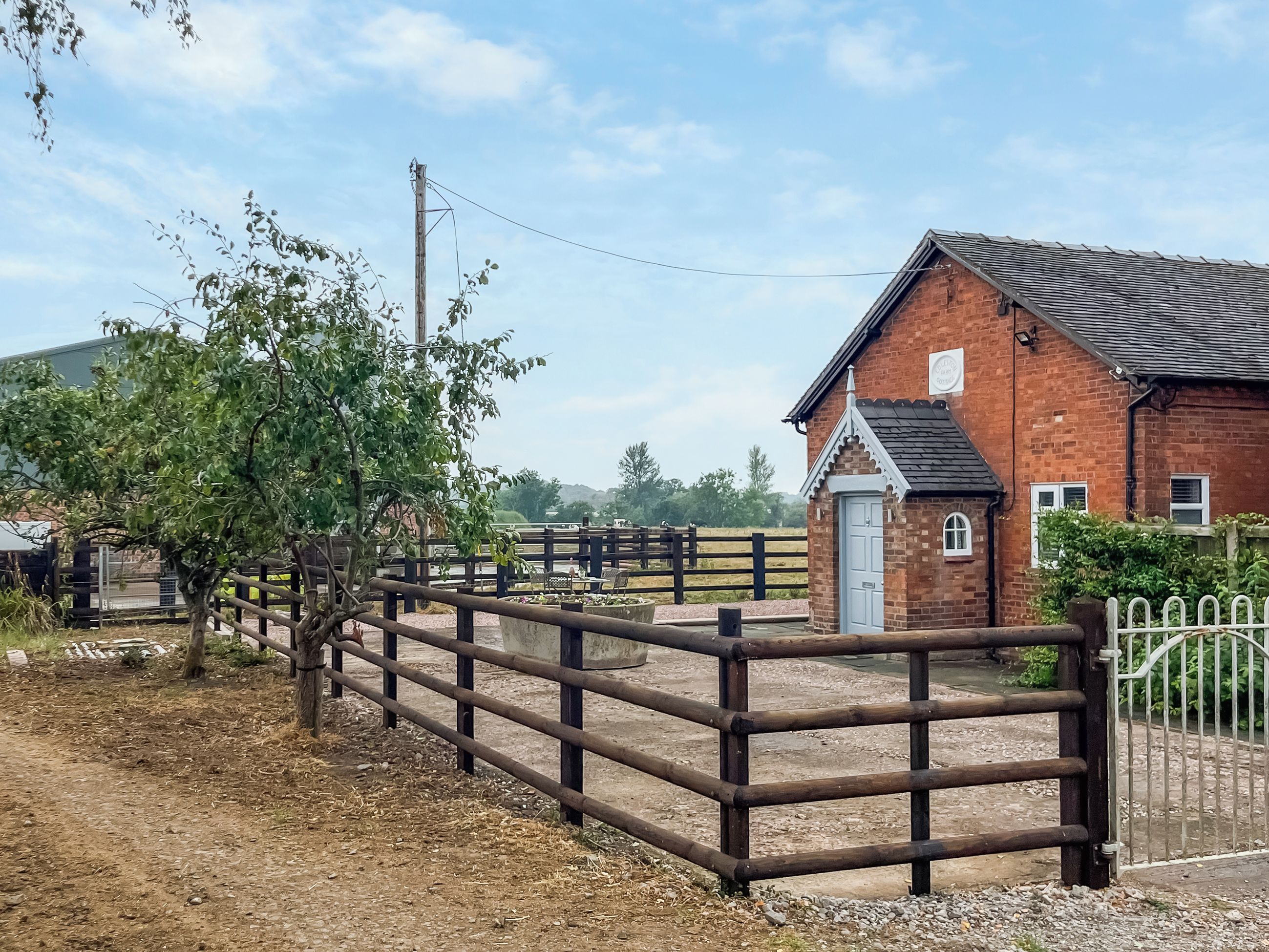 A rural property with a brick building, a wooden fence, and a tree.