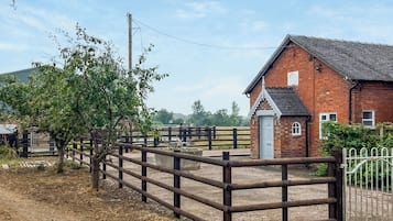 A rural property with a brick building, a wooden fence, and a tree.