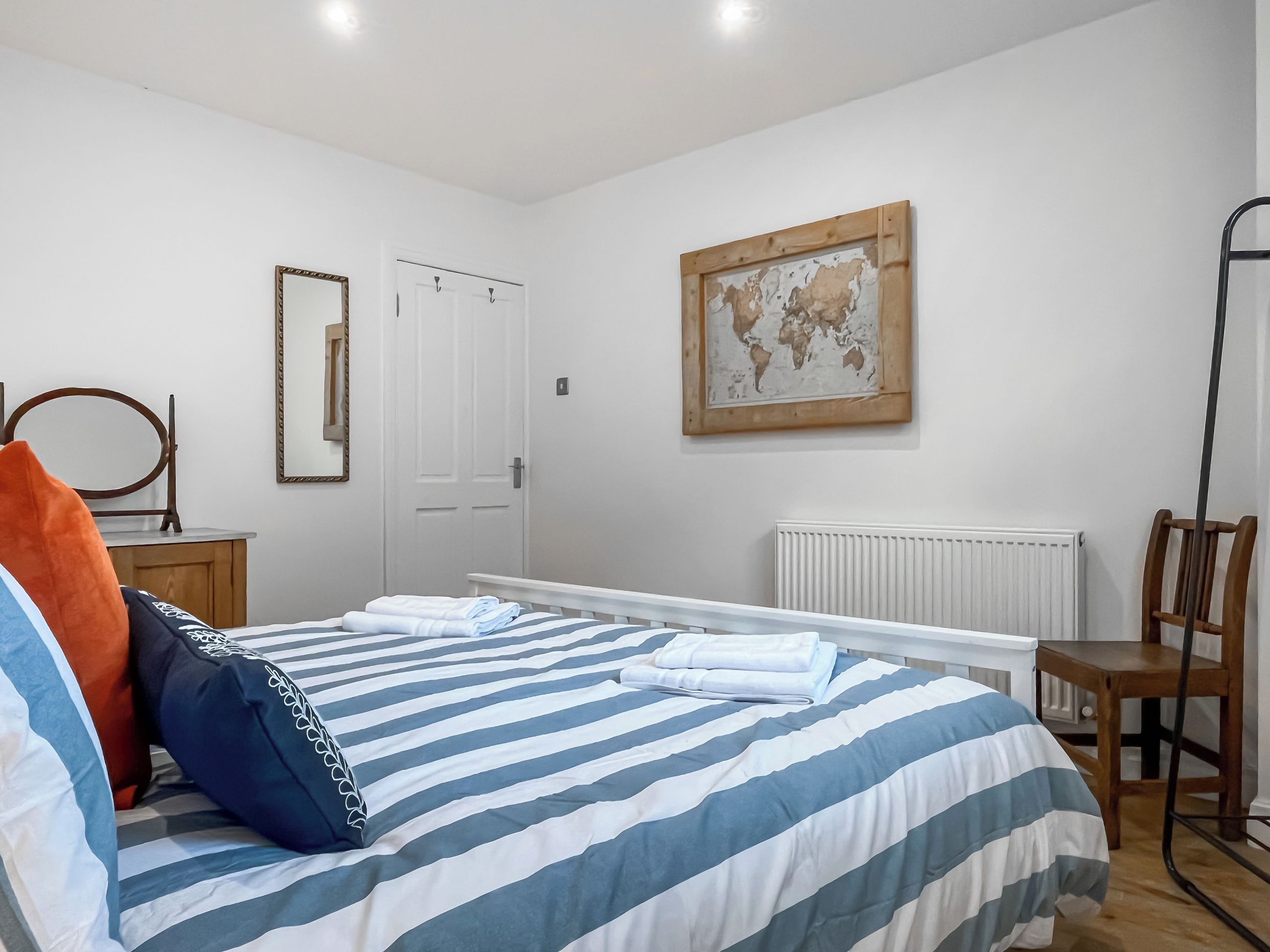 A bedroom with a bed, a chair, a radiator, a door, and a world map on the wall.