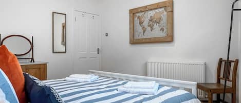 A bedroom with a bed, a chair, a radiator, a door, and a world map on the wall.