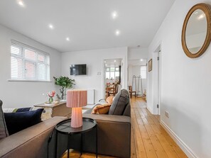 A modern living room with a sofa, a small table, a lamp, and a television on the wall. - Edleston Farm Cottage - UK52358 (Edleston, near Nantwich)