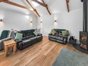 A cozy living room with a fireplace, two leather sofas with cushions, a wooden coffee table, and a blue rug.