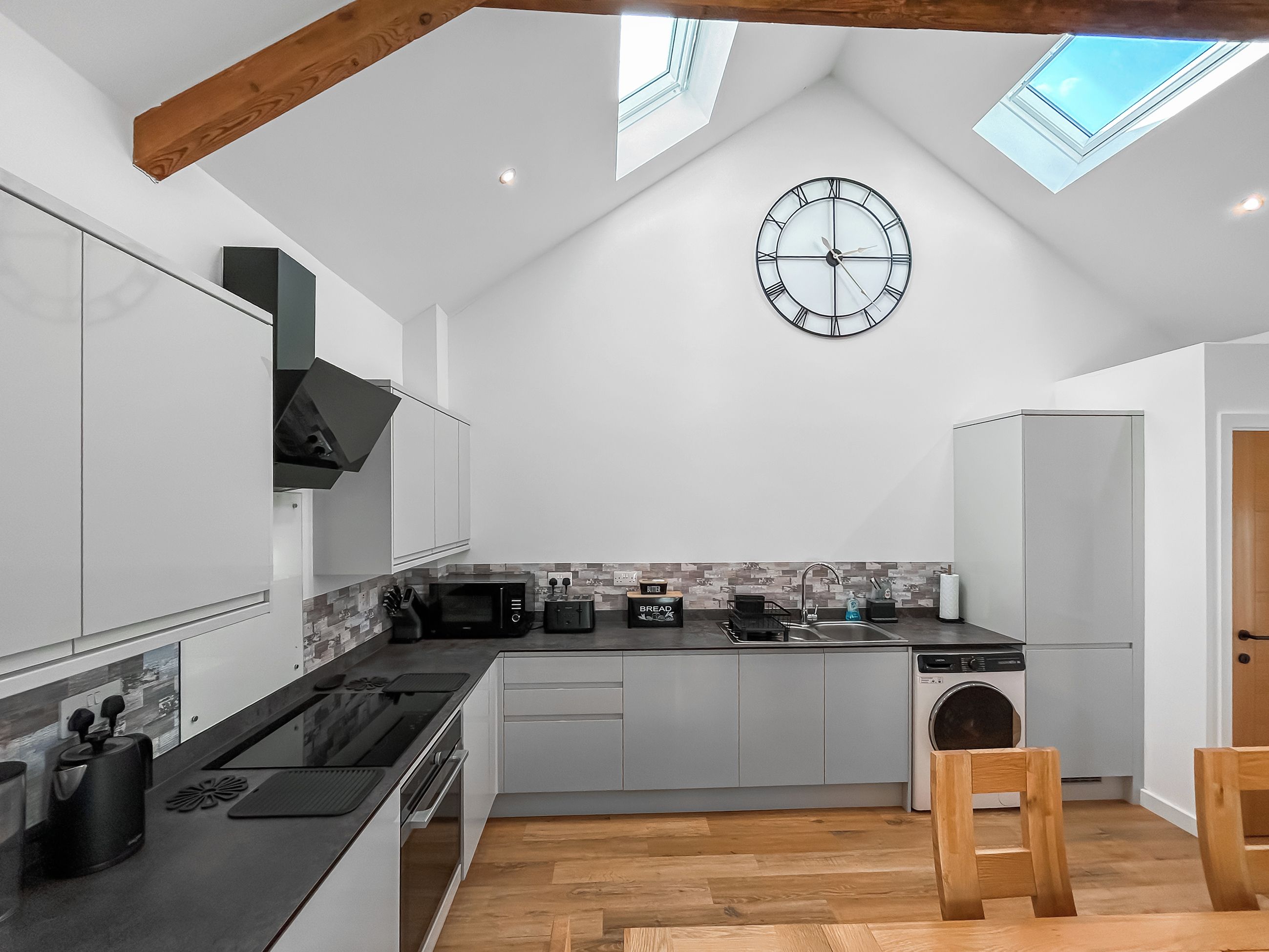 A modern kitchen with a skylight, a clock, and a built-in washing machine.