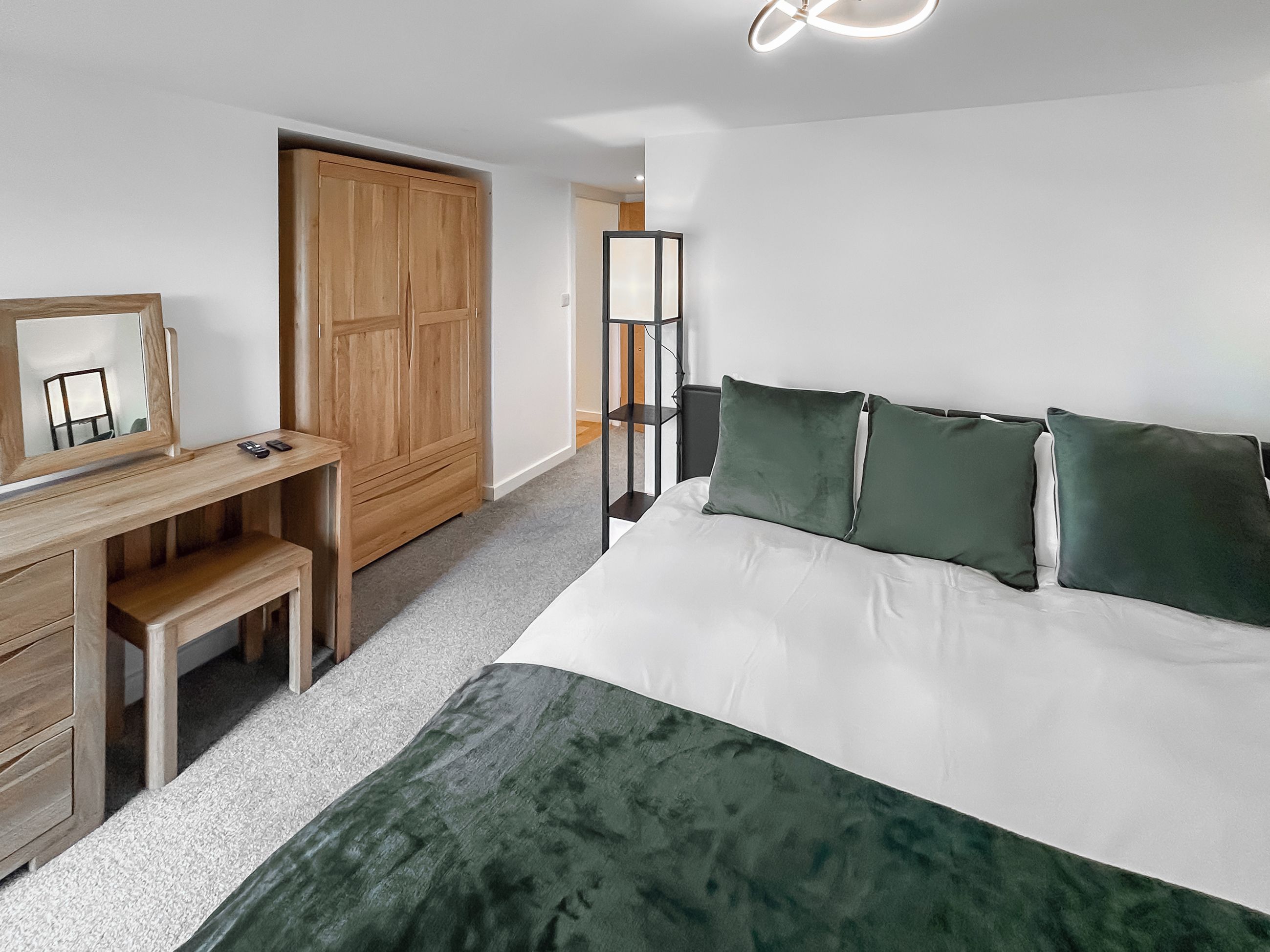 A bedroom with a bed, a desk, a wardrobe, and a mirror.