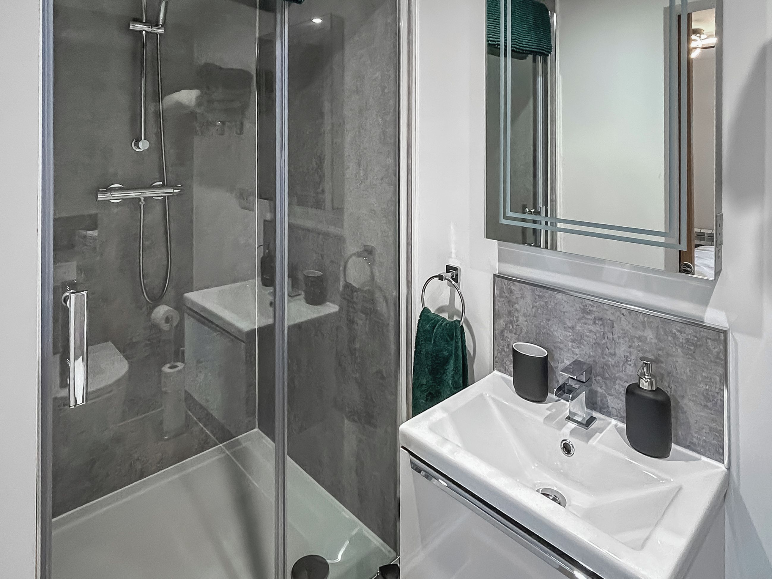Une salle de bain moderne avec une douche à parois de verre, un lavabo blanc et un miroir au-dessus.