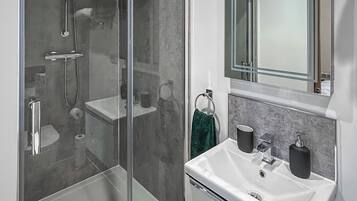 Une salle de bain moderne avec une douche à parois de verre, un lavabo blanc et un miroir au-dessus.