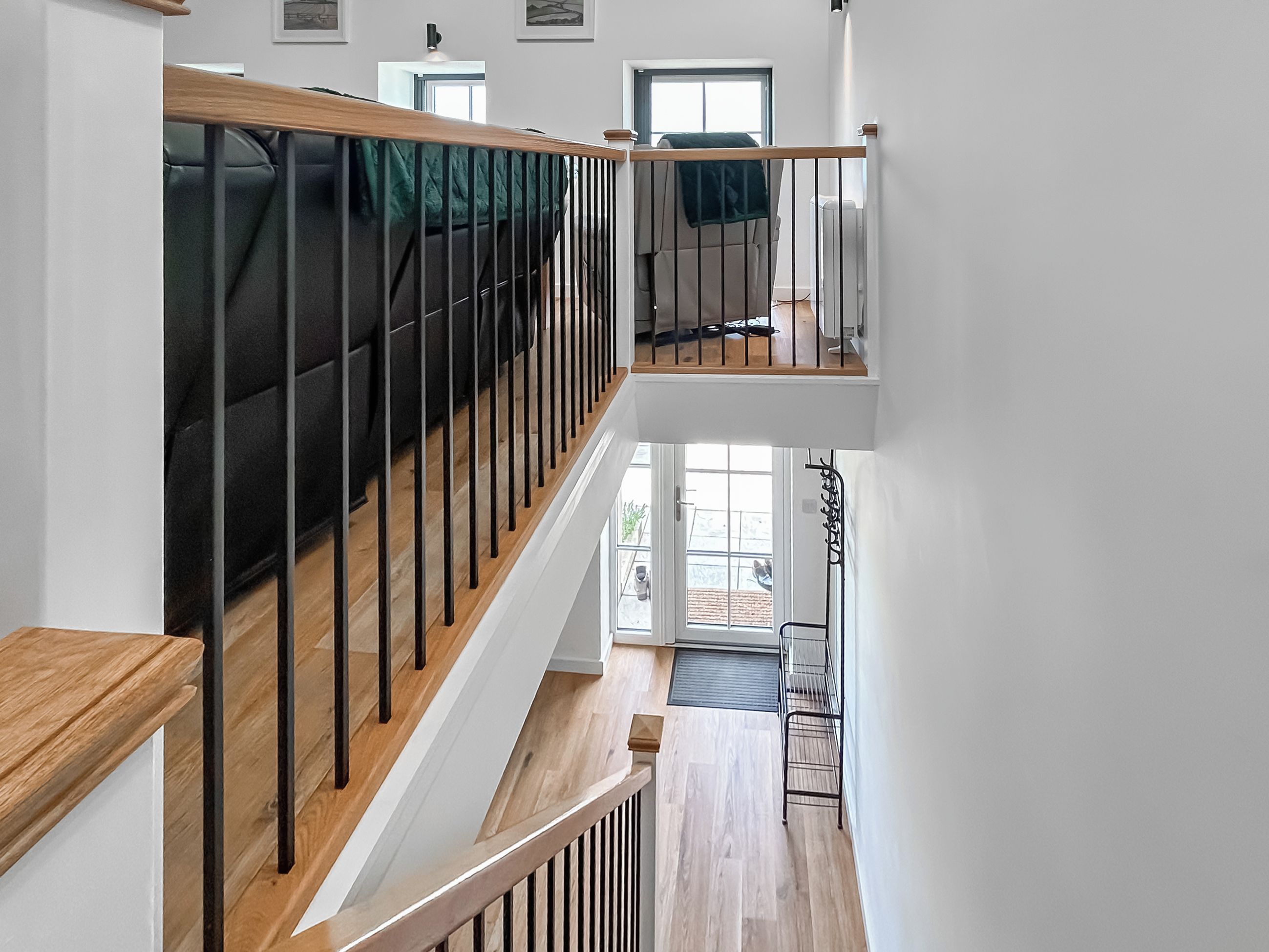 Interior de varios niveles con barandillas de madera, una escalera y vistas al exterior.