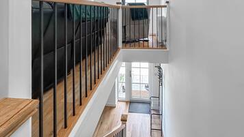 Interior de varios niveles con barandillas de madera, una escalera y vistas al exterior.