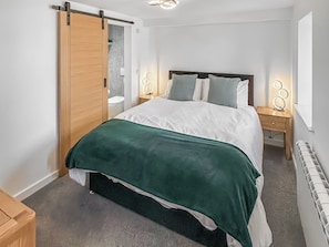 Une chambre à coucher comprenant un lit, une porte coulissante, des tables de chevet avec des lampes et un radiateur.