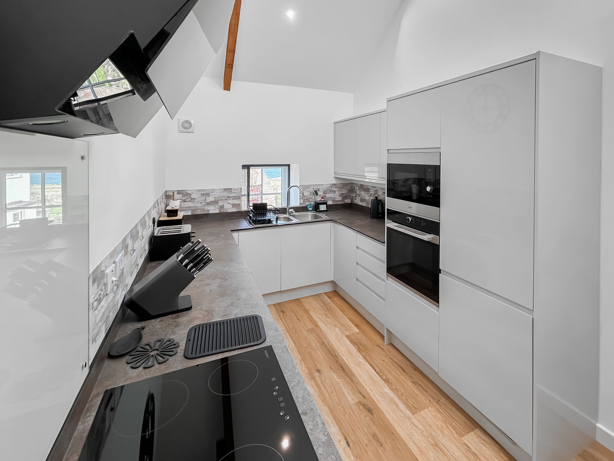 A modern kitchen with a built-in oven, a stove, and a sink.