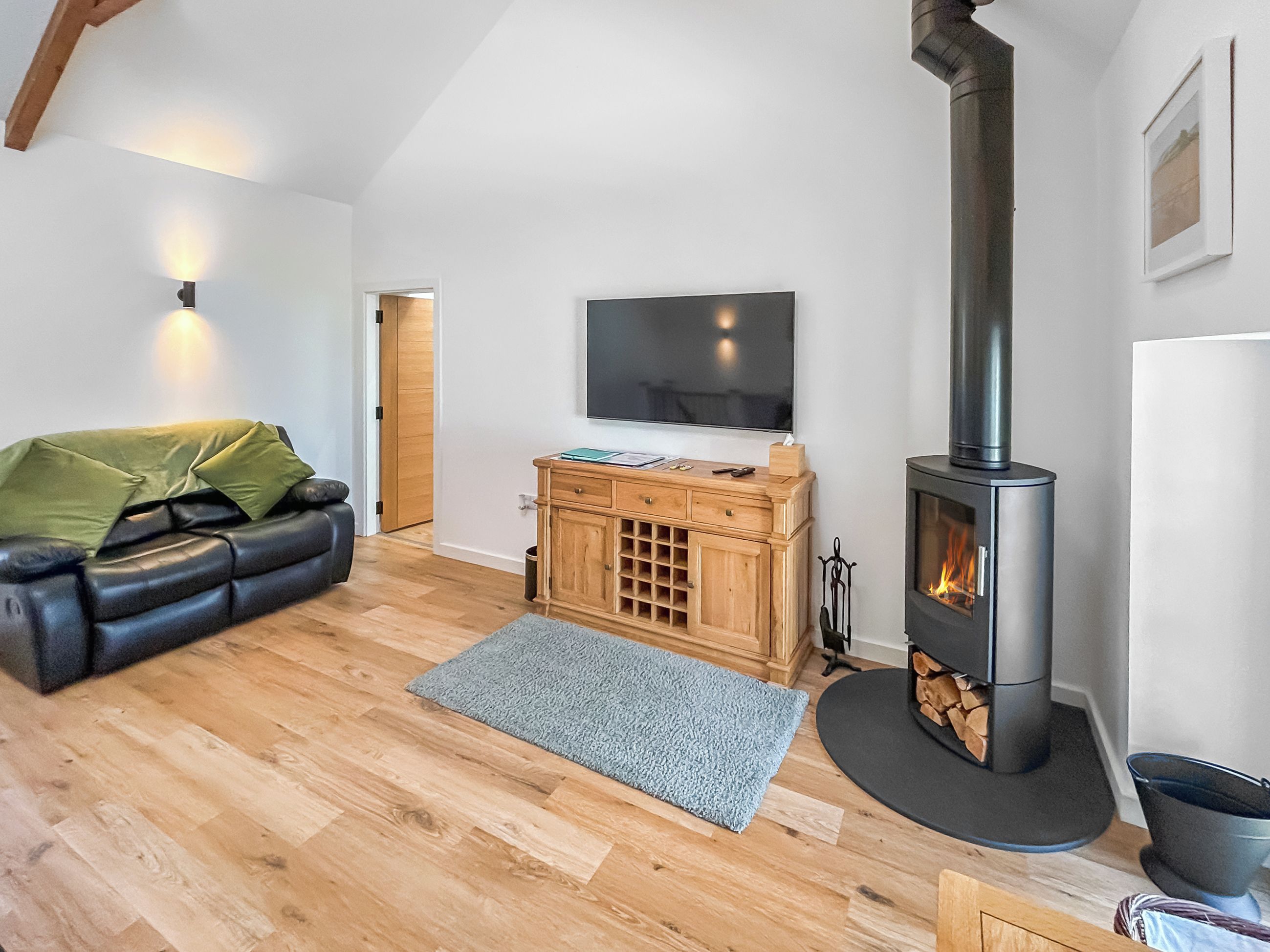 Una sala de estar acogedora con chimenea, un sofá, un televisor y un aparador de madera.