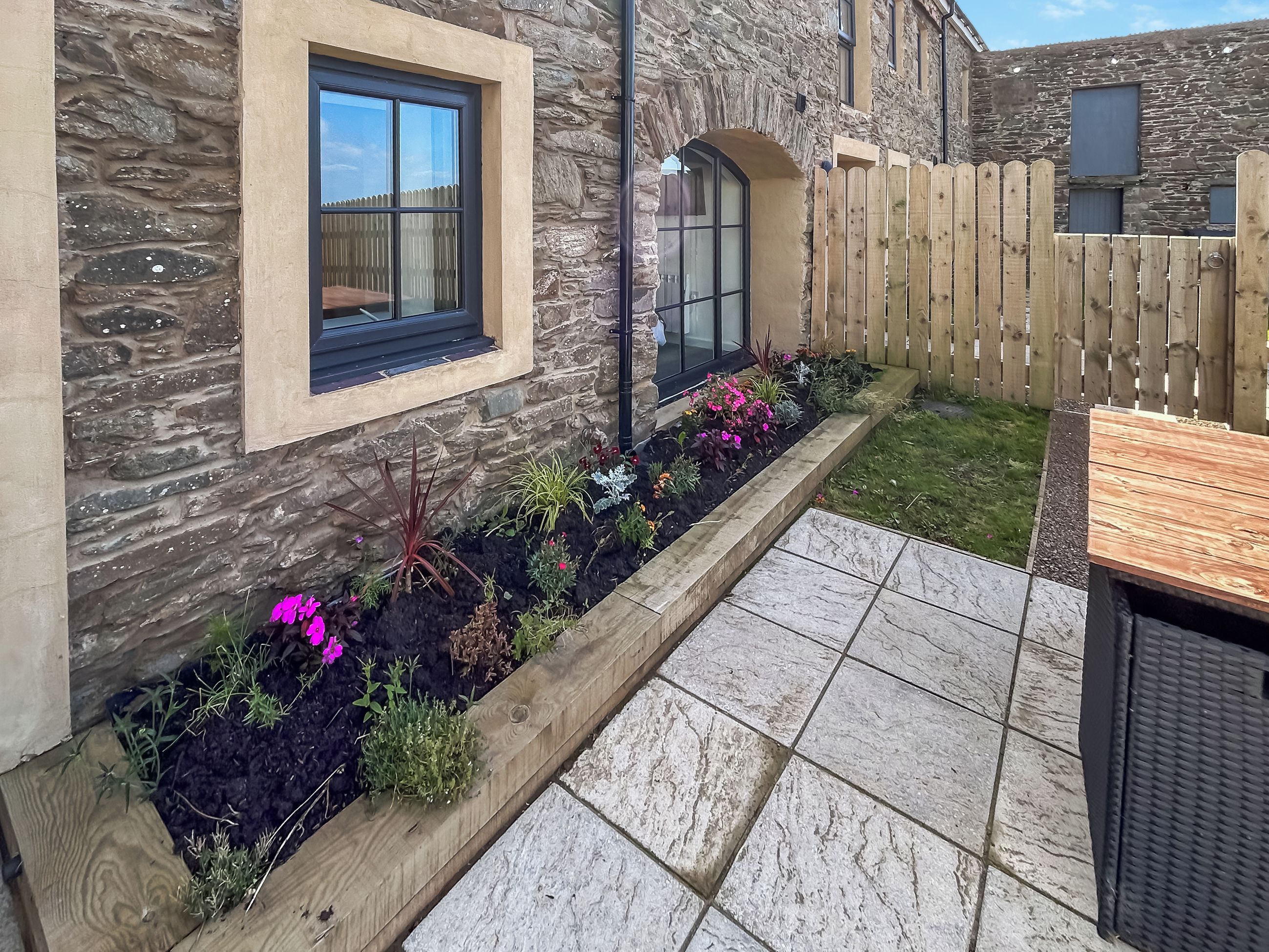 A stone building with a window and a wooden fence.