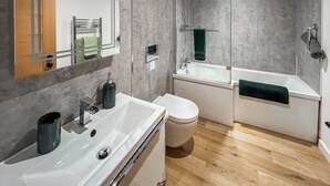 Een moderne badkamer met een wit wastafel, toilet en bad.