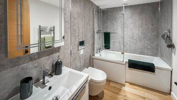 Une salle de bain moderne avec un lavabo blanc, des toilettes et une baignoire.
