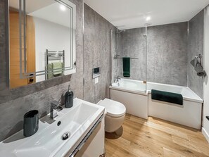 Une salle de bain moderne avec un lavabo blanc, des toilettes et une baignoire.