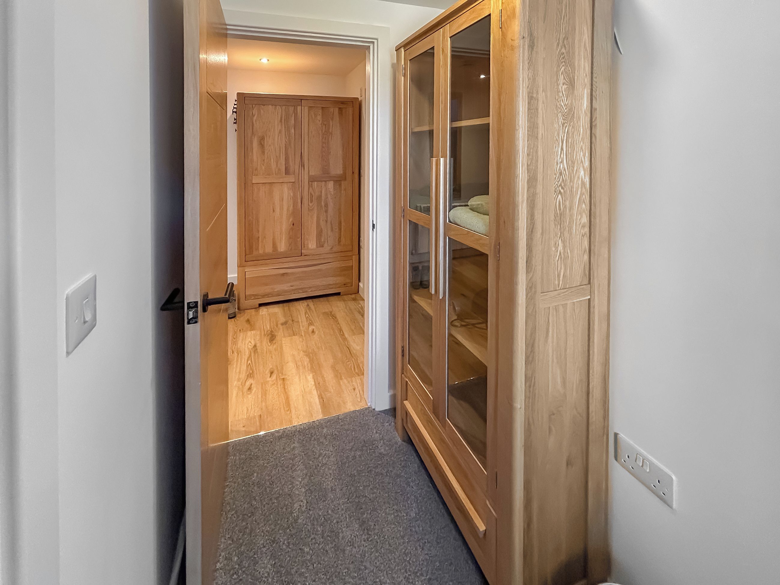 A hallway with a wooden wardrobe and a carpeted floor.