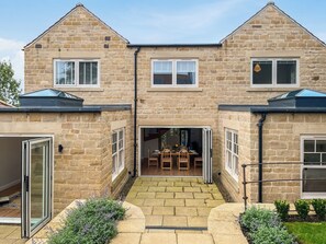 A two-story stone house with a central patio, a sliding glass door, and a small garden area. - 3 bedroom accommodation in York (York)