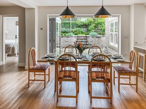 A dining area with a table set for four, wooden chairs, and a view of a garden through a glass door. - 3 bedroom accommodation in York (York)
