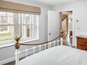 A bedroom with a bed, a window with blinds, a door, and a staircase leading to another room. - 3 bedroom accommodation in York (York)
