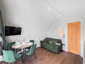 A compact living space with a dining area, a sofa, a television, and a door. - 1 bedroom accommodation in Wigglesworth (Wigglesworth)