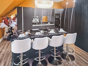 A modern kitchen with a central island, bar stools, and a chandelier. - The Riverside Atelier (Durham)