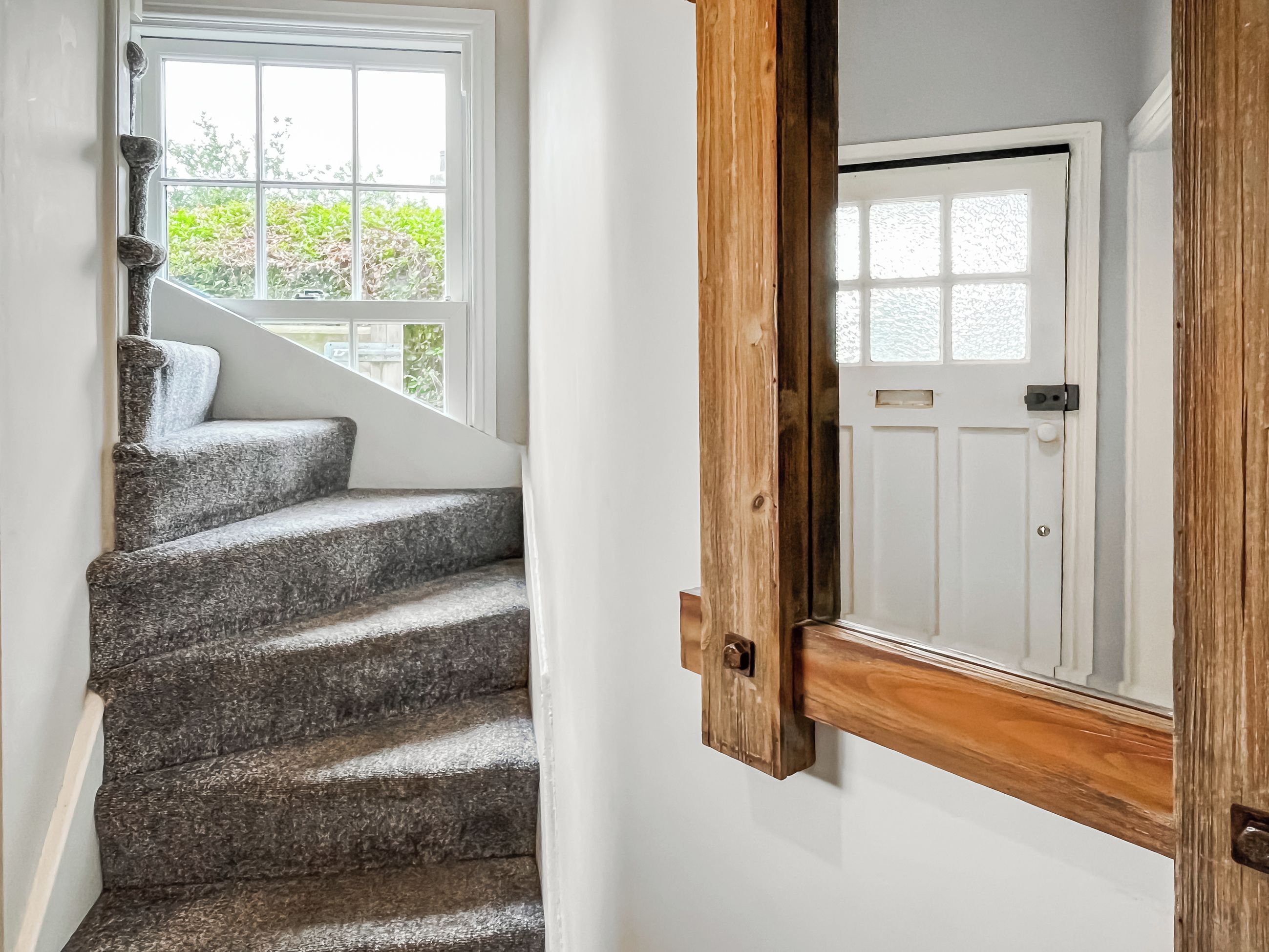 A staircase with a stone finish leading to a white door with a wooden frame.