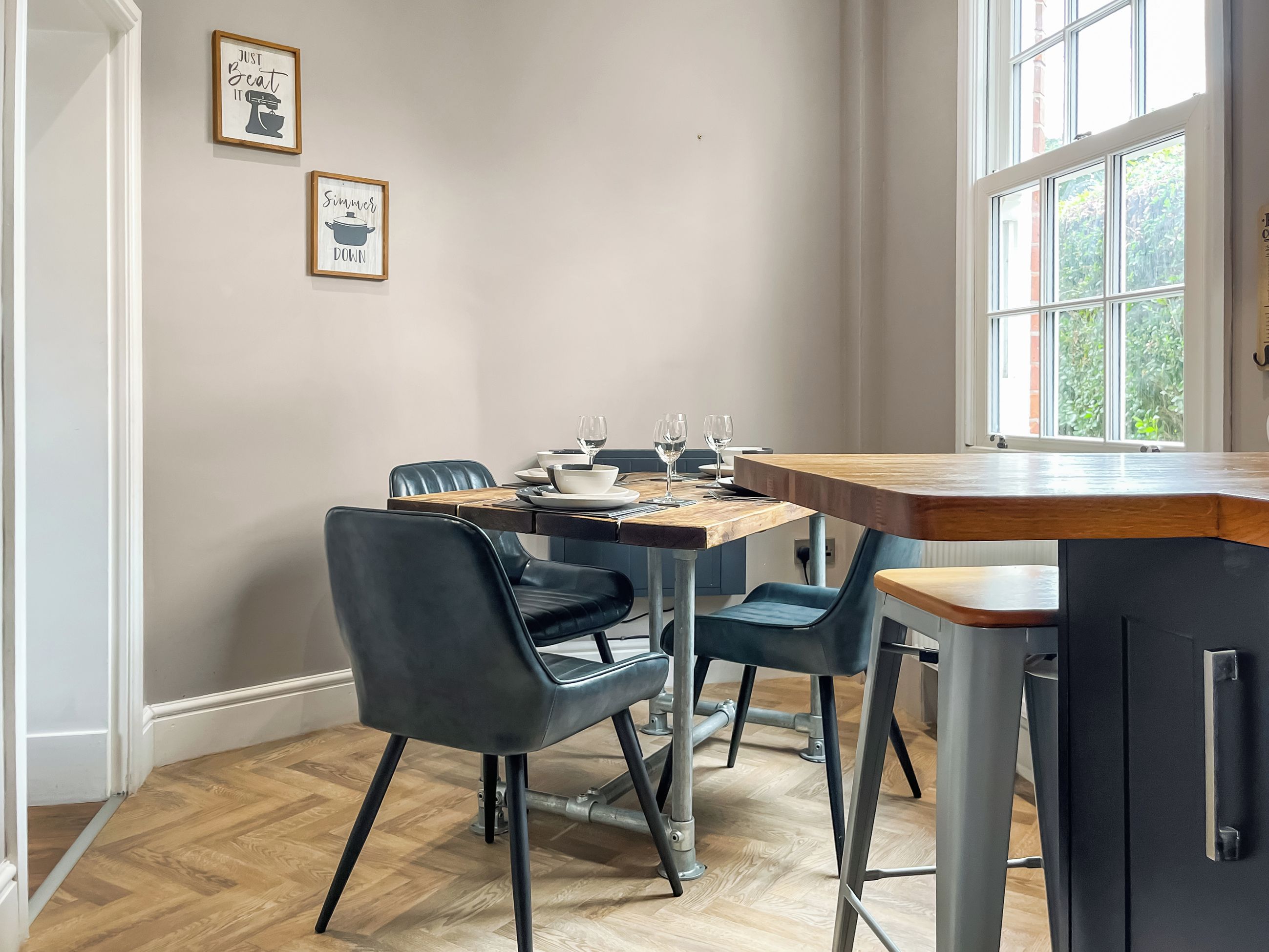 A dining area with a wooden table, black chairs, and a window with a view of greenery.