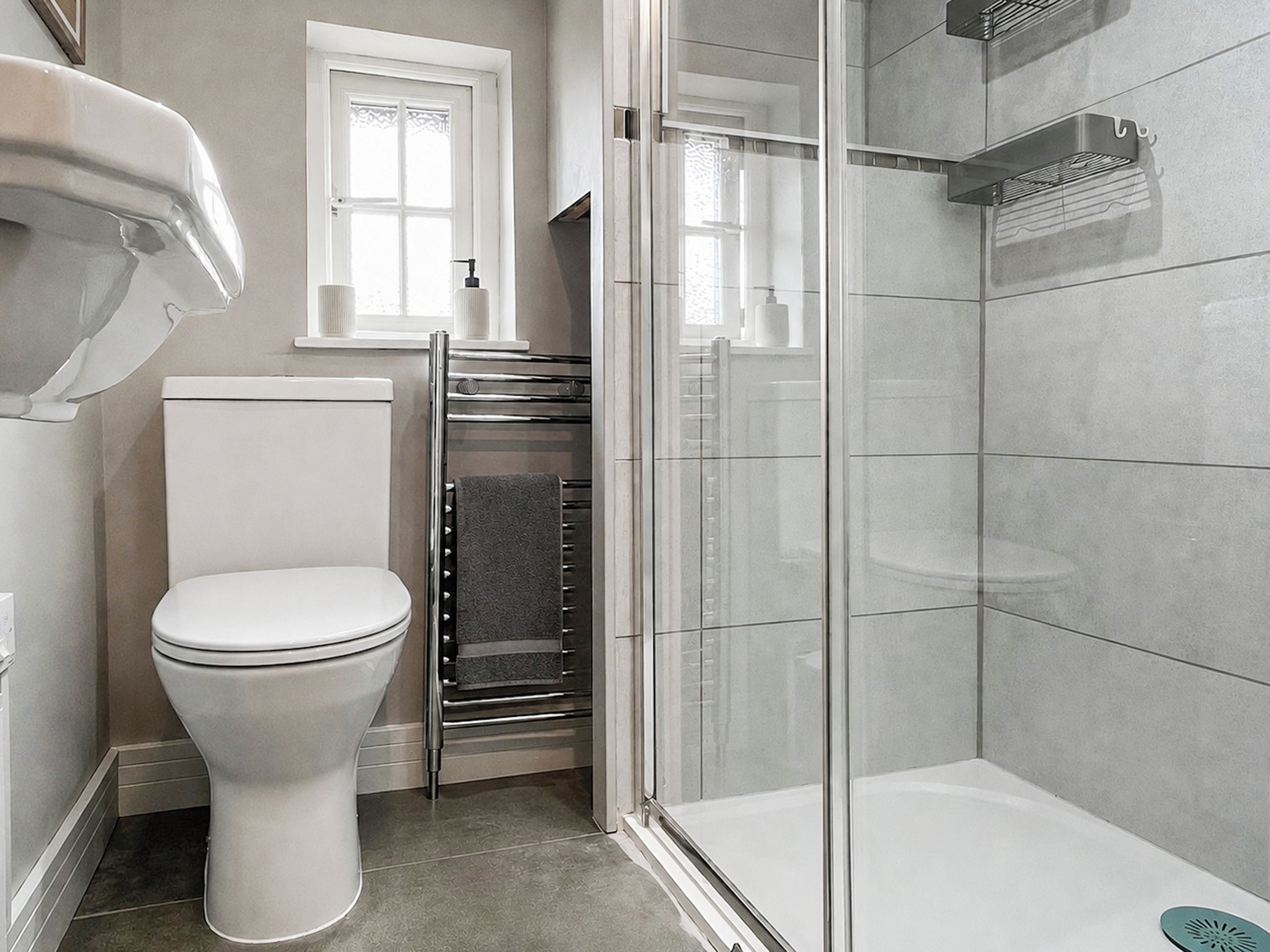 A modern bathroom with a toilet, a glass shower enclosure, and a towel rack.