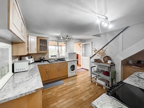 Een compacte keuken met houten kastjes, een ingebouwde wasmachine en een fornuis.