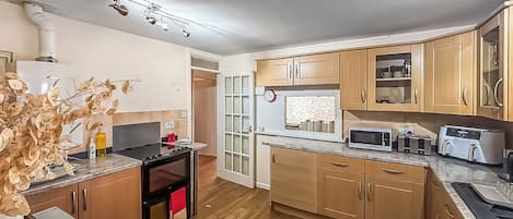 A compact kitchen with wooden cabinets, a microwave, a toaster, and a stove.