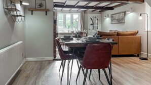 Un'area pranzo con un tavolo di legno, sedie rosse e un divano marrone.