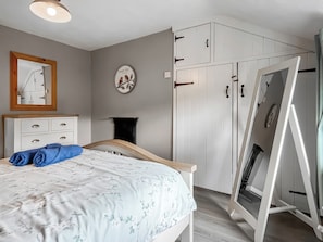 A bedroom with a bed, a dresser, a wardrobe, and a mirror.