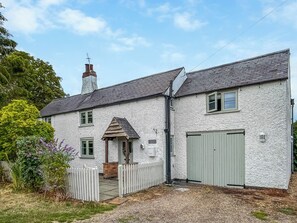 A two-story house with a white exterior, a chimney, and a fenced garden area. - 4 bedroom accommodation in Old Dalby (Old Dalby)