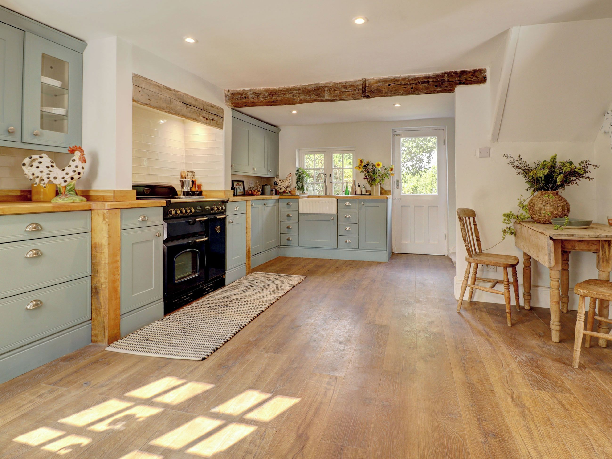 A kitchen with wooden flooring, a built-in oven, and light blue cabinets.