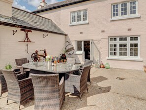 A patio with a round glass table surrounded by wicker chairs, a rustic wooden bench, and a potted plant. - 4 bedroom accommodation in Shirrell Heath (Shirrell Heath)