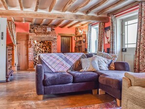 A cozy living room with a wooden ceiling, a brick wall, and a sofa with a colorful blanket. - 4 bedroom accommodation in Horsham Saint Faith (Horsham Saint Faith)