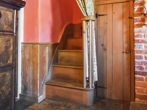 A wooden staircase with a handrail, leading to a door with a wooden frame. - 4 bedroom accommodation in Horsham Saint Faith (Horsham Saint Faith)