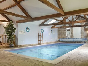 An indoor swimming pool with a tiled floor, wooden beams, and a stone wall. - The Old School House (Kirkbymoorside)
