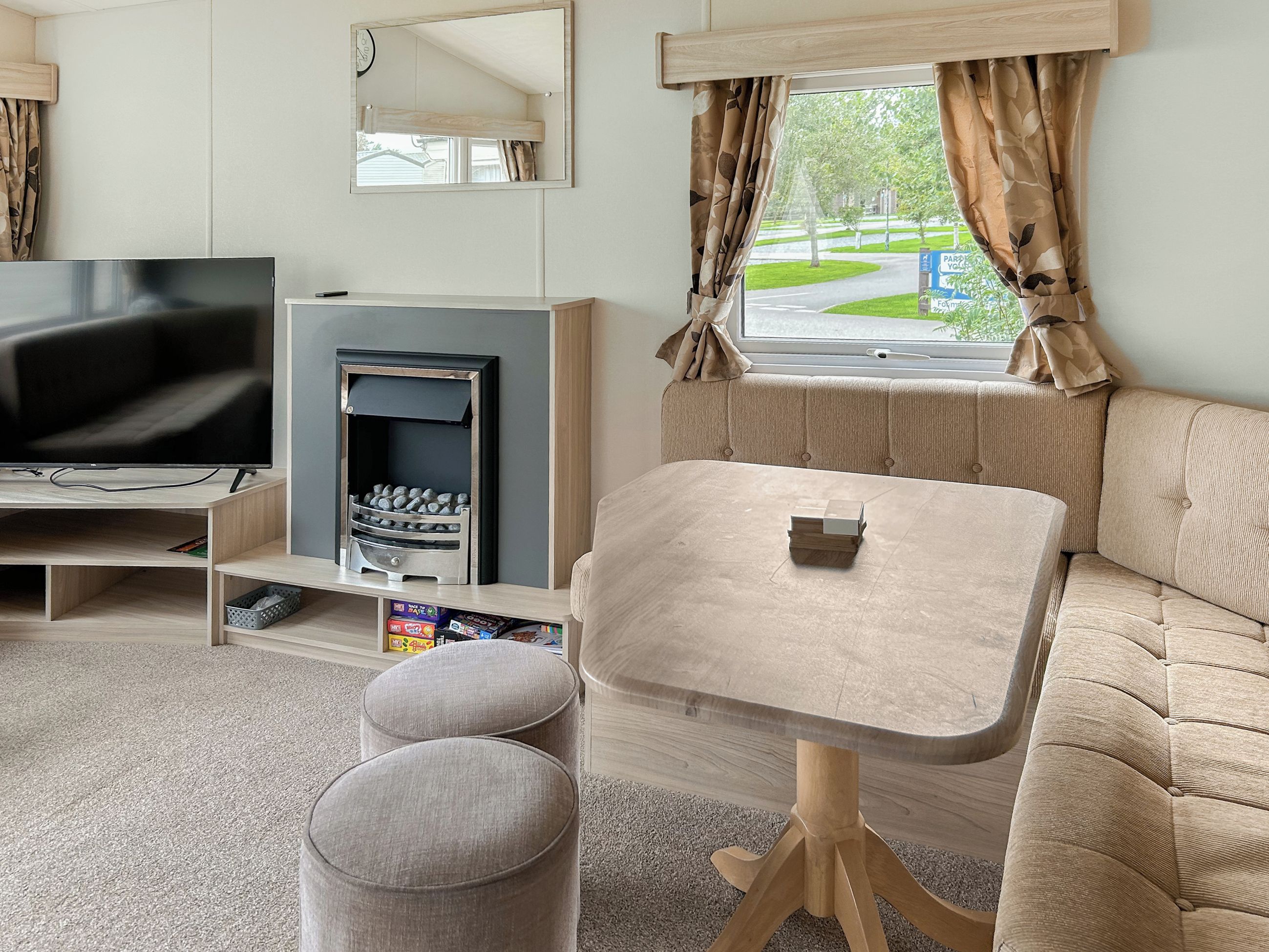 A modern living room with a flat-screen TV, a fireplace, a sofa, and a small table.