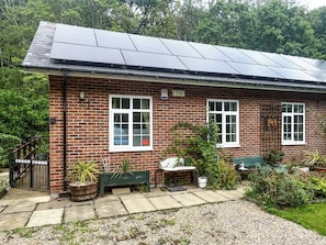Ein Gebäude aus Ziegelsteinen mit Solarmodulen, einer Bank und einem mit 'HOODS WATER' beschrifteten Tor.