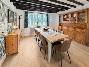 A dining area with a wooden table, chairs, and a cabinet with glassware. - 5 bedroom accommodation in Oswestry (Shropshire)