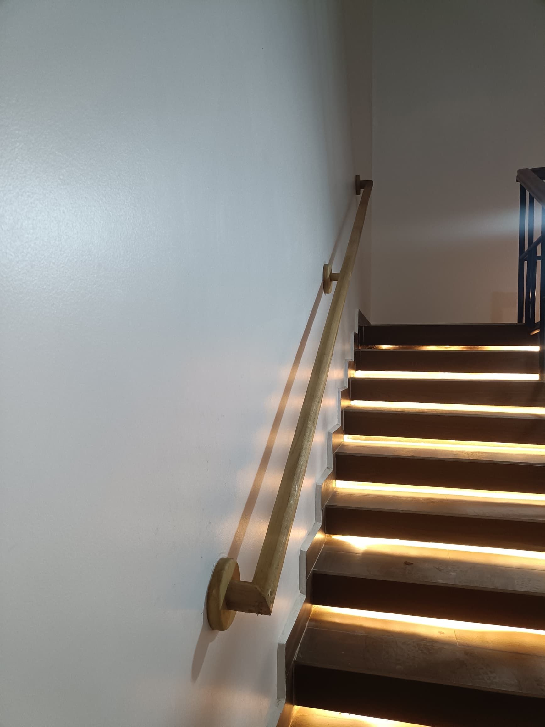 Eine Treppe mit Handlauf, beleuchtet durch Umgebungslicht.