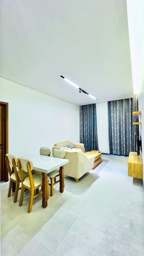 Uma sala de estar moderna com área de jantar, sofás e mesa de centro.