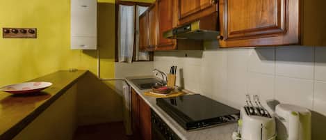A compact kitchen with wooden cabinets, a built-in oven, a sink, and a toaster.