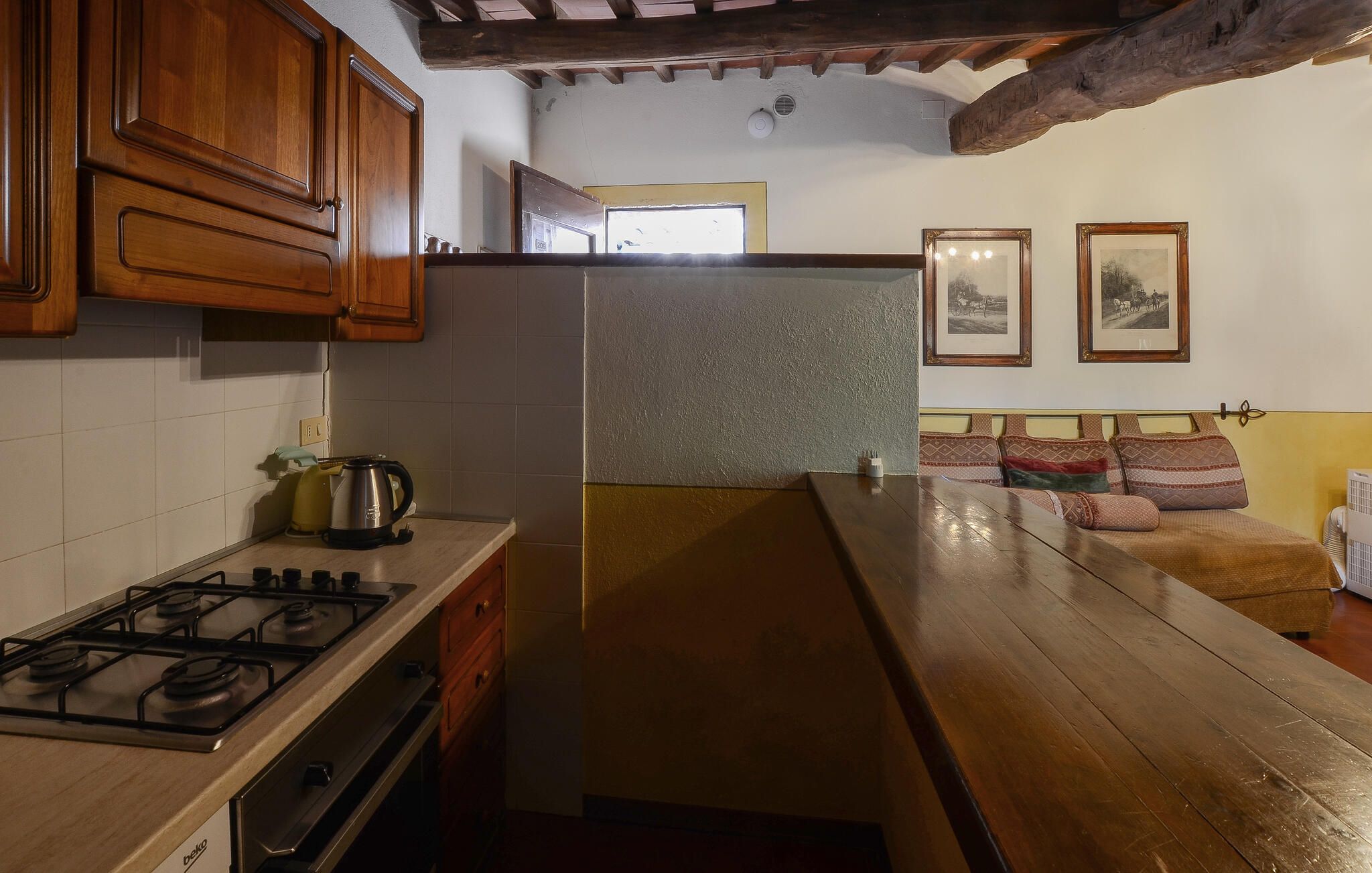Une cuisine avec des meubles de rangement en bois, une cuisinière à gaz, un réfrigérateur et une table à manger en bois.