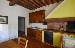 A kitchen with wooden cabinets, a brick oven, and a dining area with a table and chairs. - Beautiful home in Murlo with house a panoramic view (Murlo)