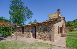 A stone building with a tiled roof, a wooden door, and a small porch area. - Beautiful home in Murlo with house a panoramic view (Murlo)